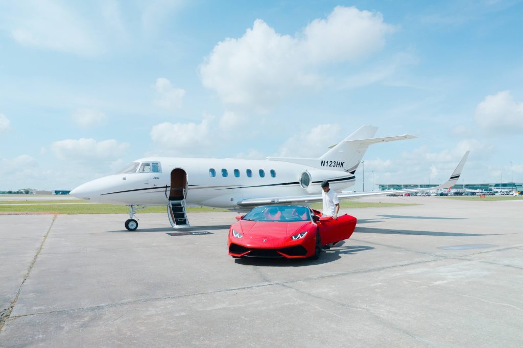 Red Lamborghini Aventador parked in front of a private jet at Houston airport for media production