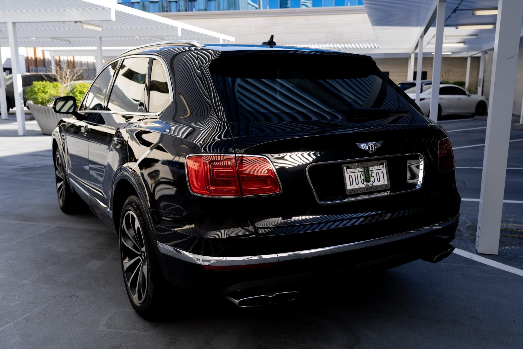 Rear angle of black Bentley Bentayga SUV with Texas plates, parked outdoors.