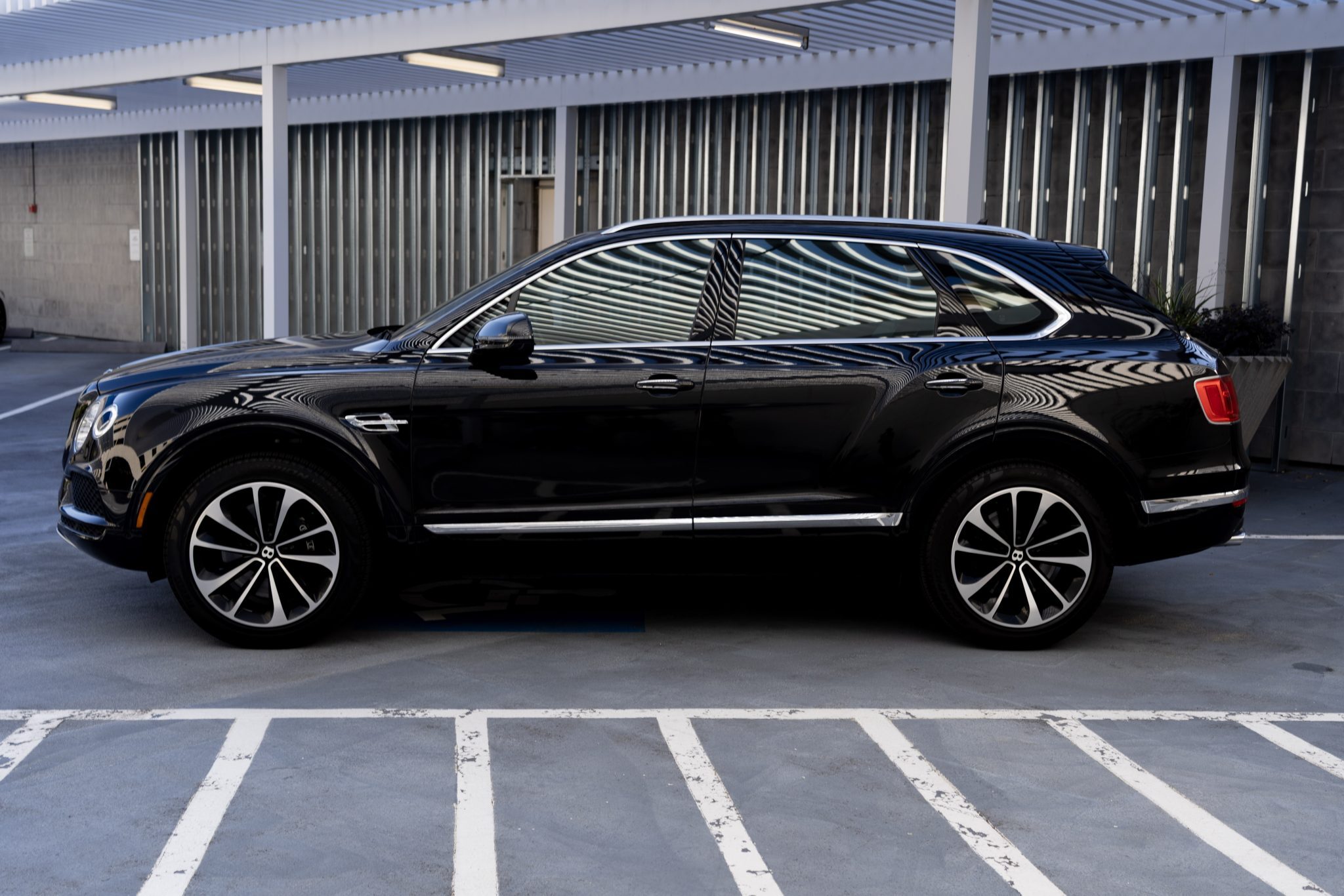 Black Bentley Bentayga shown from a side angle, parked in an urban lot.