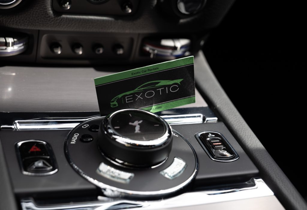 Exotic business card placed on the center console of a Rolls Royce, showcasing Houston’s premier exotic car rental service