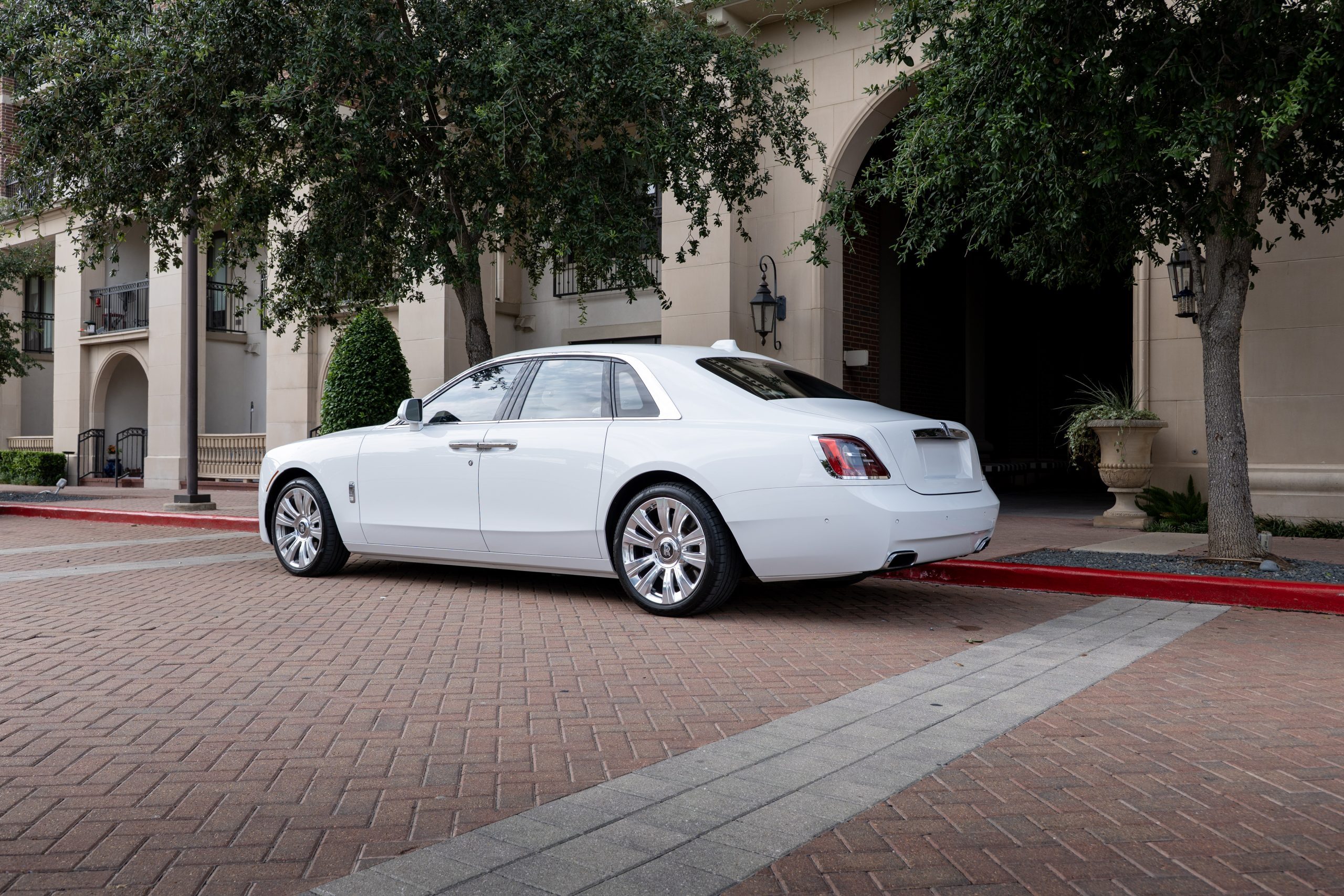 White Rolls Royce Ghost, rear view showing sculpted bumper, LED tail lamps, and luxury badging.