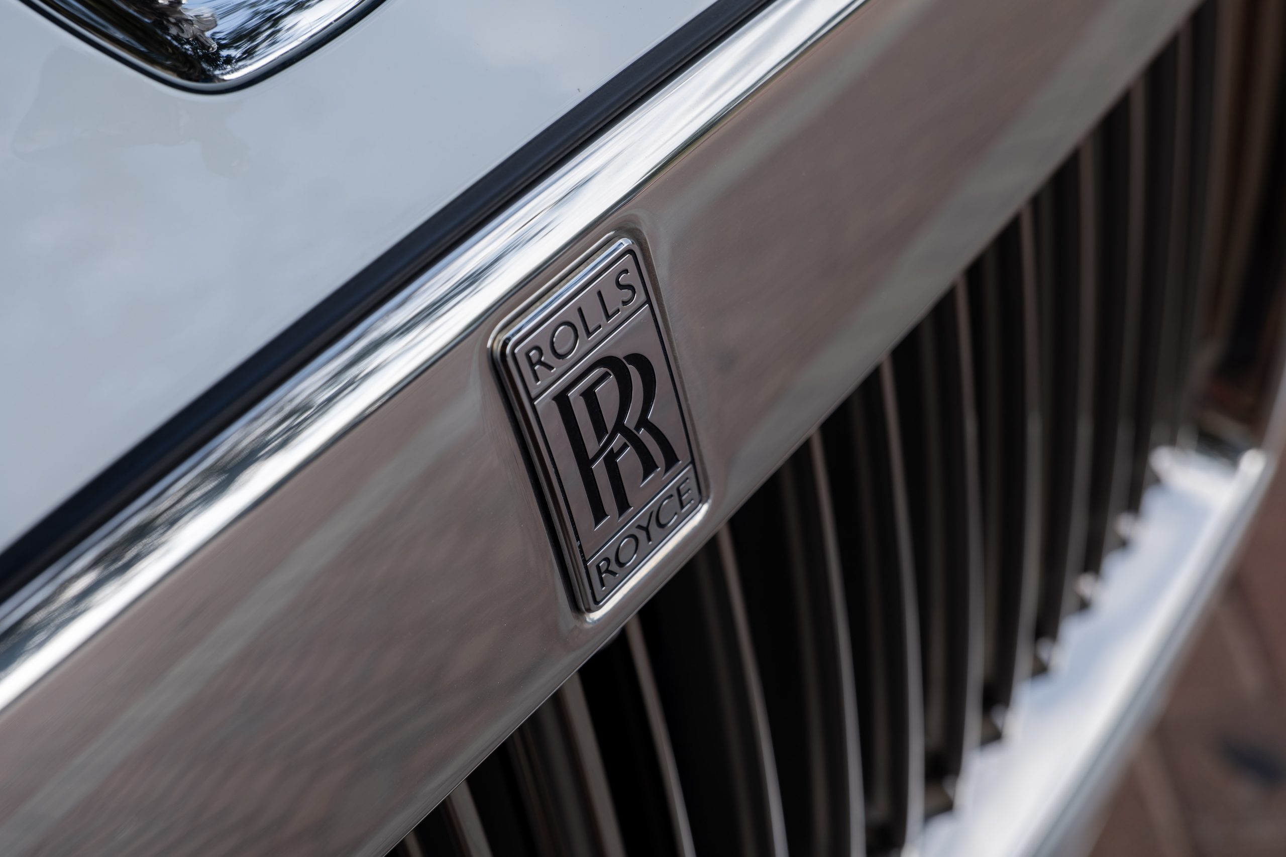 Detailed view of Rolls Royce Ghost’s chrome grille with iconic double-R badge centered.