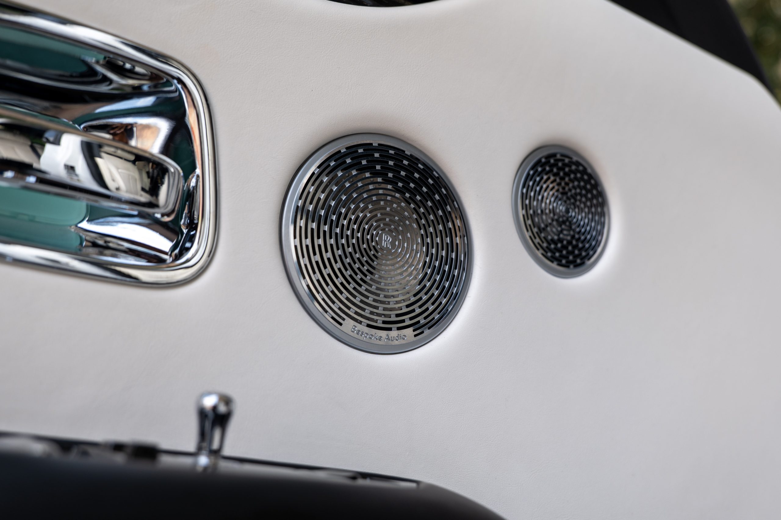 Rolls Royce Ghost chrome Bespoke Audio speaker grilles set in white leather door panel.