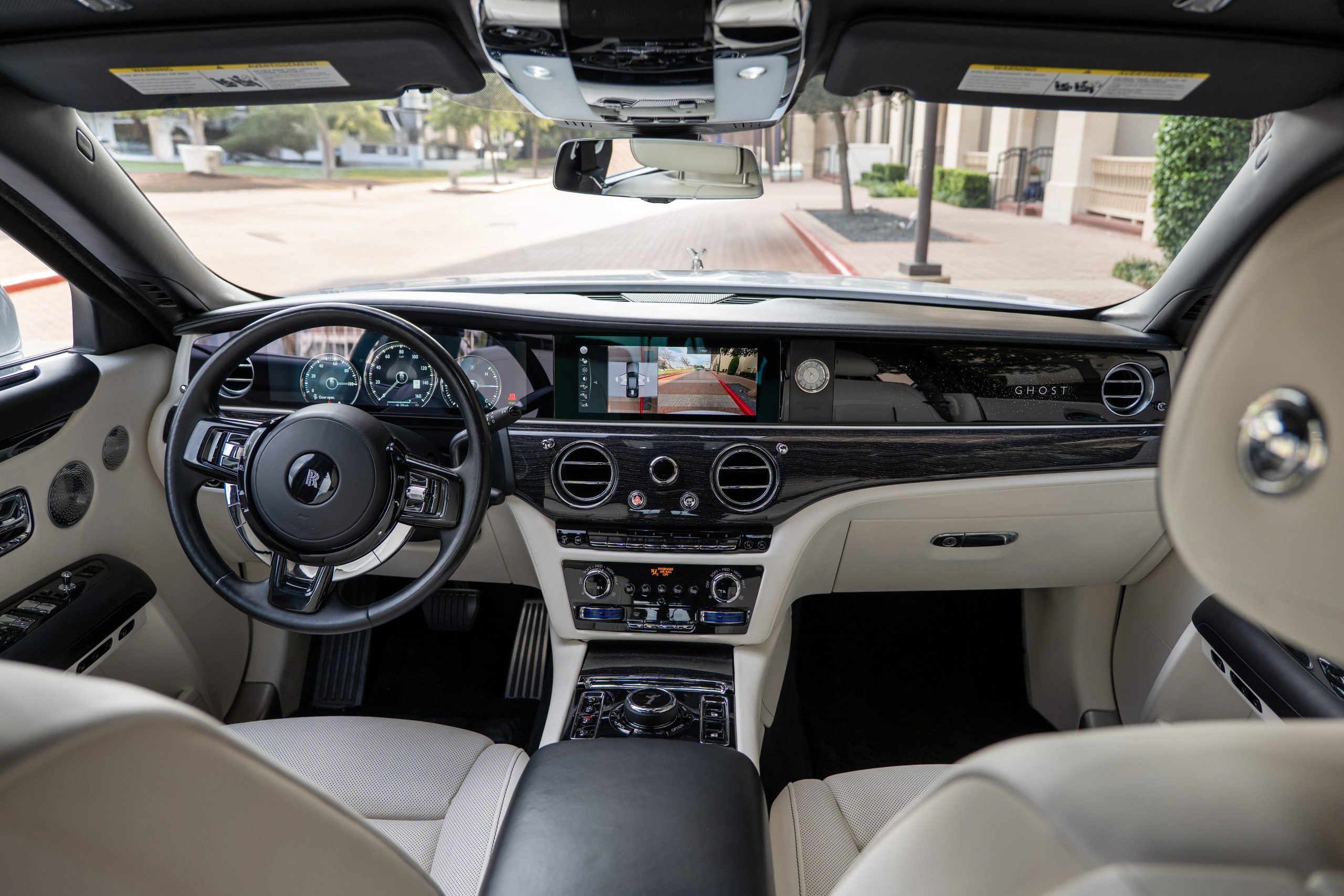 Detailed view of Rolls Royce Ghost cockpit with leather steering wheel, digital display, and high-gloss accents.