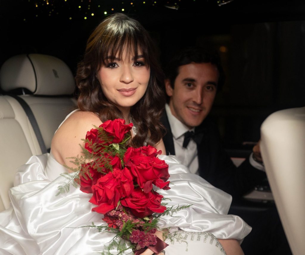 Bride holding a red rose bouquet inside a Rolls Royce Cullinan with chauffeur service by iExotic at a luxury wedding in Houston