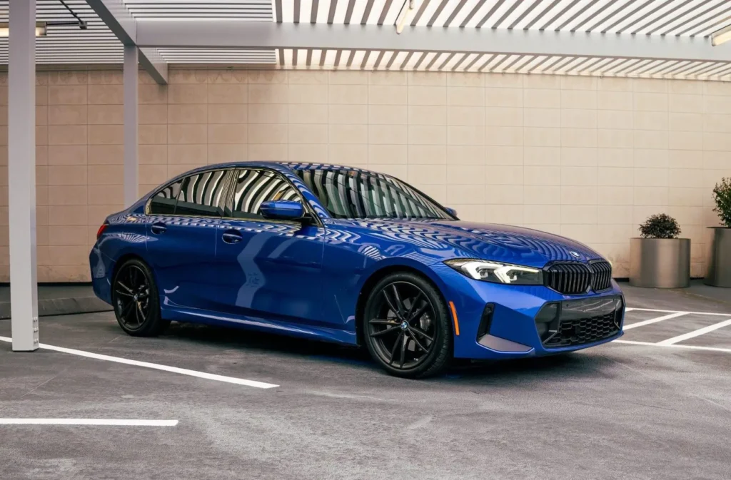 blue BMW 330i Houston rental angled front side view in modern covered parking