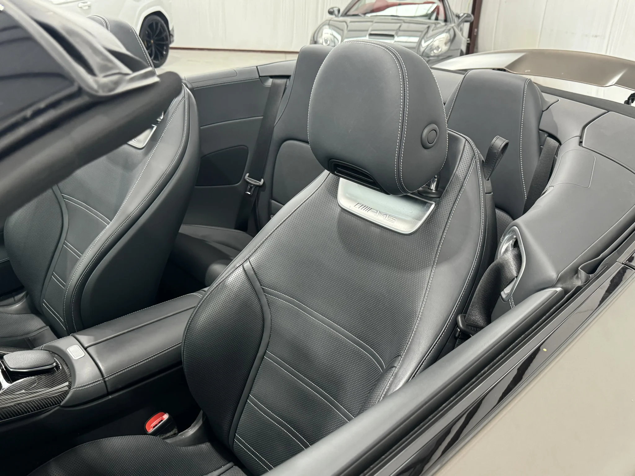 View of the Mercedes SL63 AMG’s rear passenger seating, with stitched leather, contoured padding, and stylish dark trim.